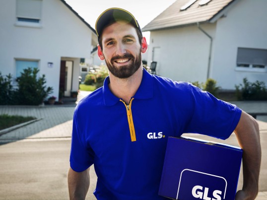 GLS delivery driver with a parcel on a street