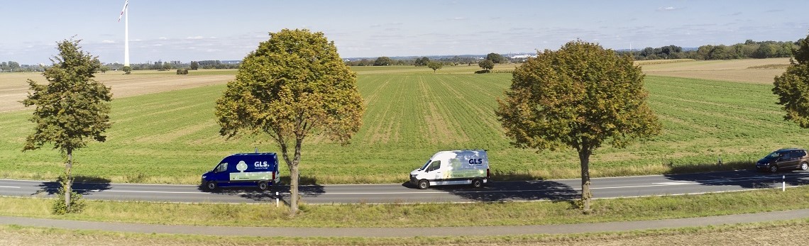 Zwei GLS-Zustellfahrzeuge fahren auf einer Landstraße