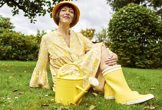 Smiling woman with watercan in field