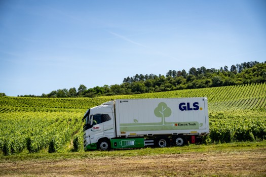 Camion électrique GLS circulant au milieu de vignes, illustrant l’engagement de l’entreprise pour un transport durable et zéro émission nette.