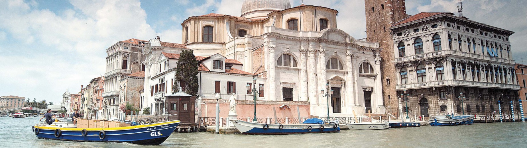 GLS delivery boat transporting parcels on a canal in Venice, representing GLS France’s European delivery network.