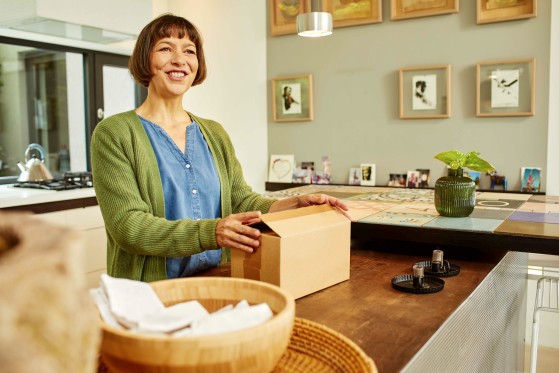 smiling woman opening a parcel in the kitchen