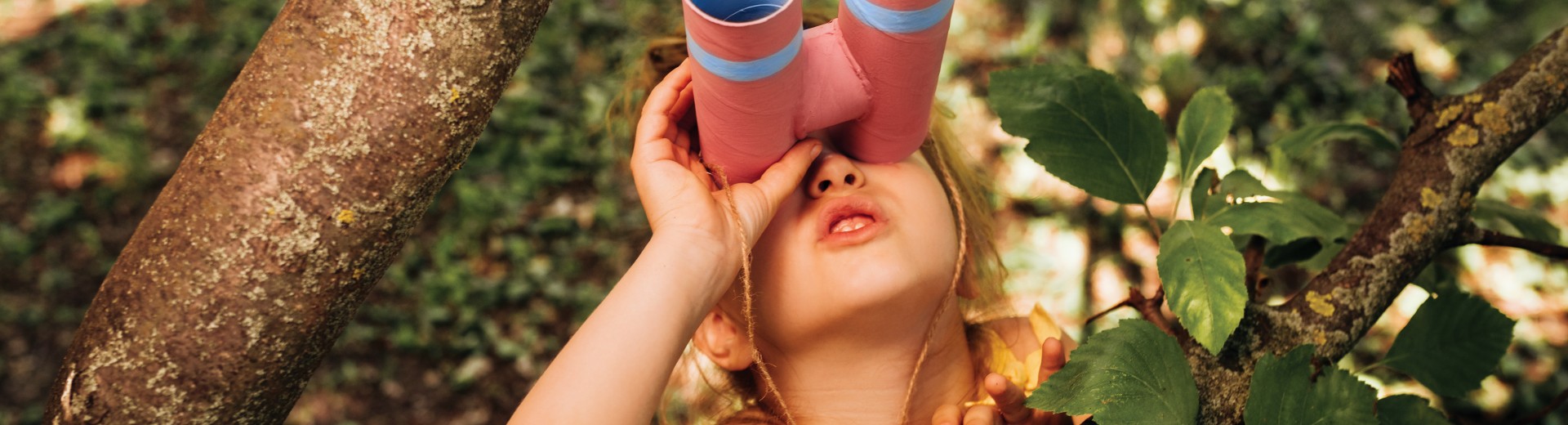 The little girl with binoculars is playing in the tree