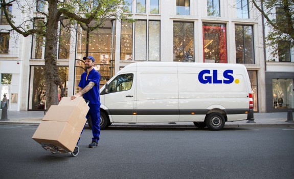 GLS courier handling parcels with a GLS van in the background