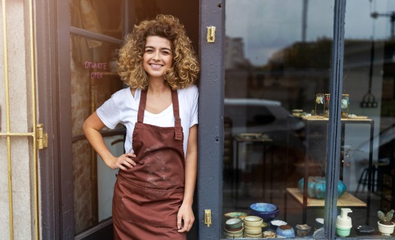 Woman shop owner smiling in front of her shop
