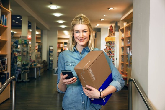 Woman with parcel and calculator in the shop