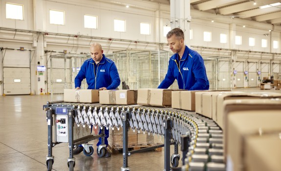 Two employees sorting packages on a conveyor