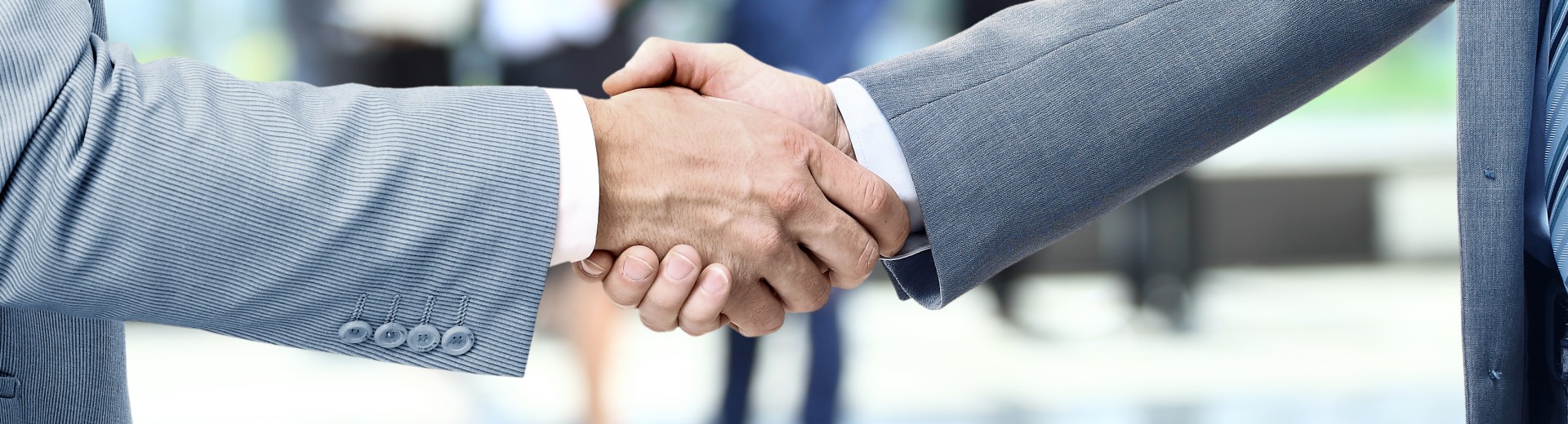 Hands reaching out for a business handshake in front of a professional setting.